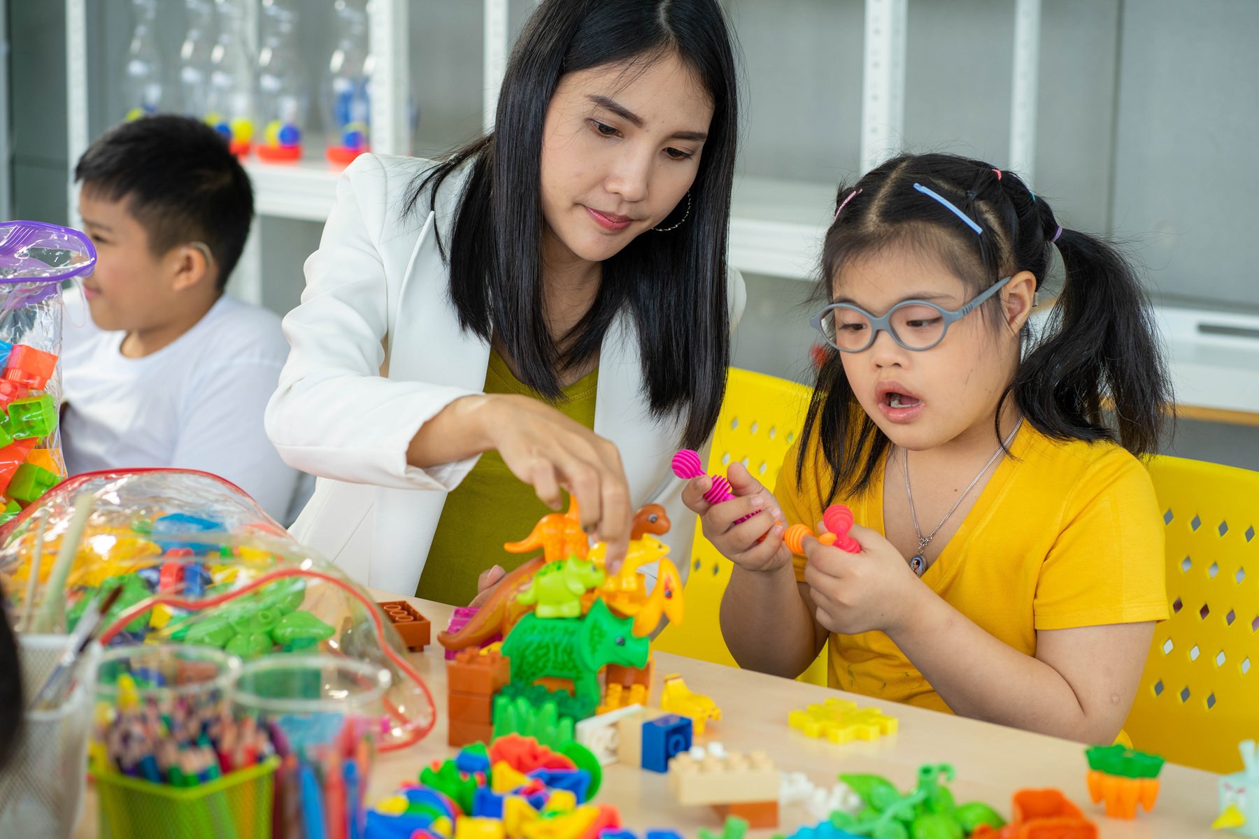 Girl with DownSyndrome Learning in Classroom with Teacher